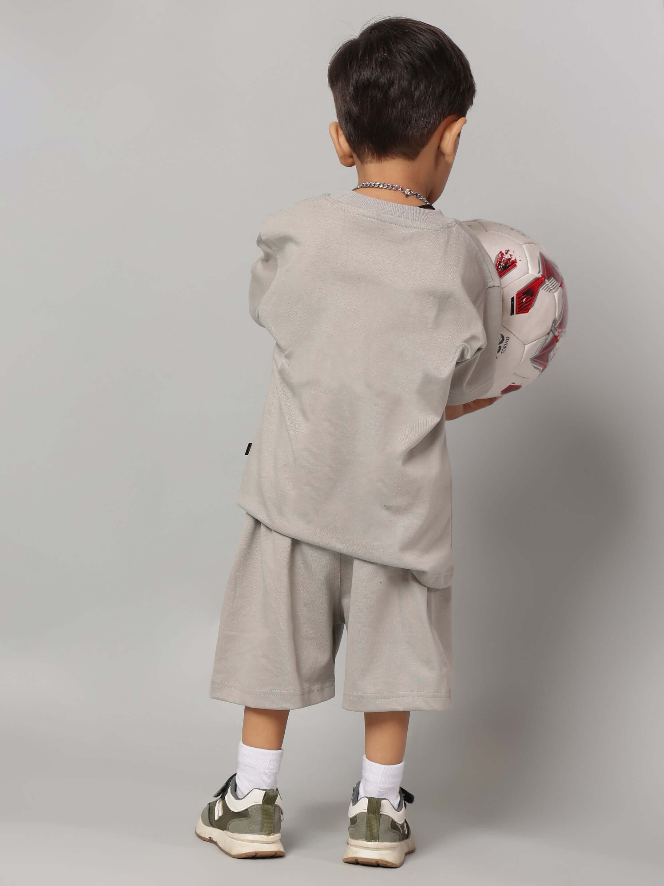 Child wearing Futuristic Kids Co-ord for Boys Girls Grey holding a soccer ball, showcasing modern and trendy style for boys and girls.