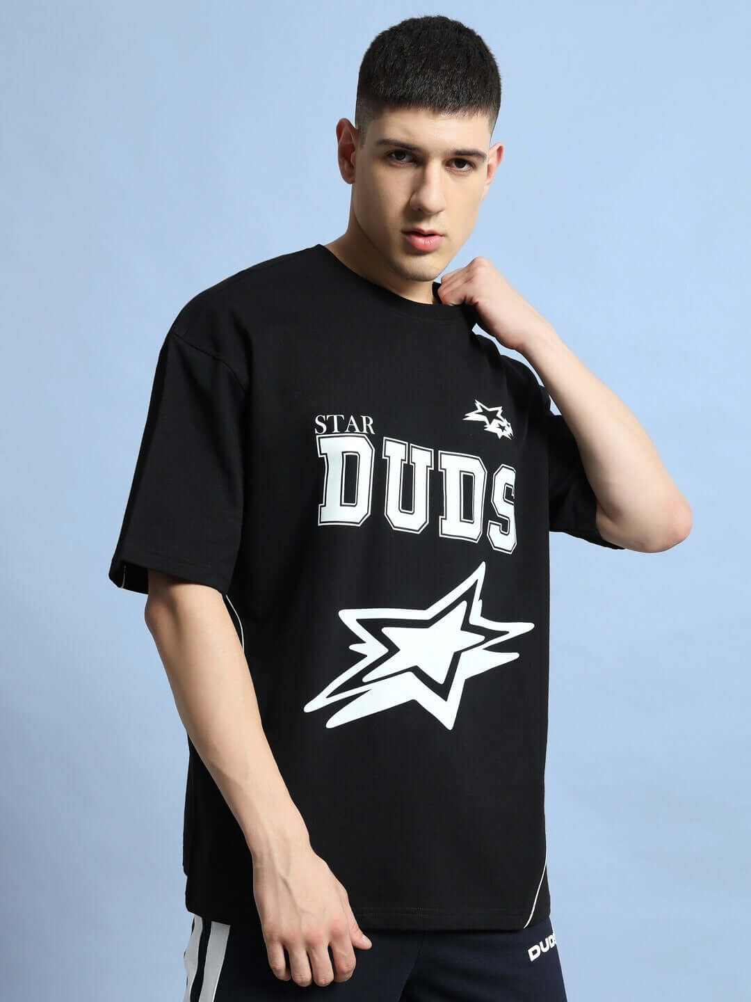 Model wearing Galaxy oversized black T-shirt by DUDS with star and logo print, showcasing custom fit option for tailored comfort.
