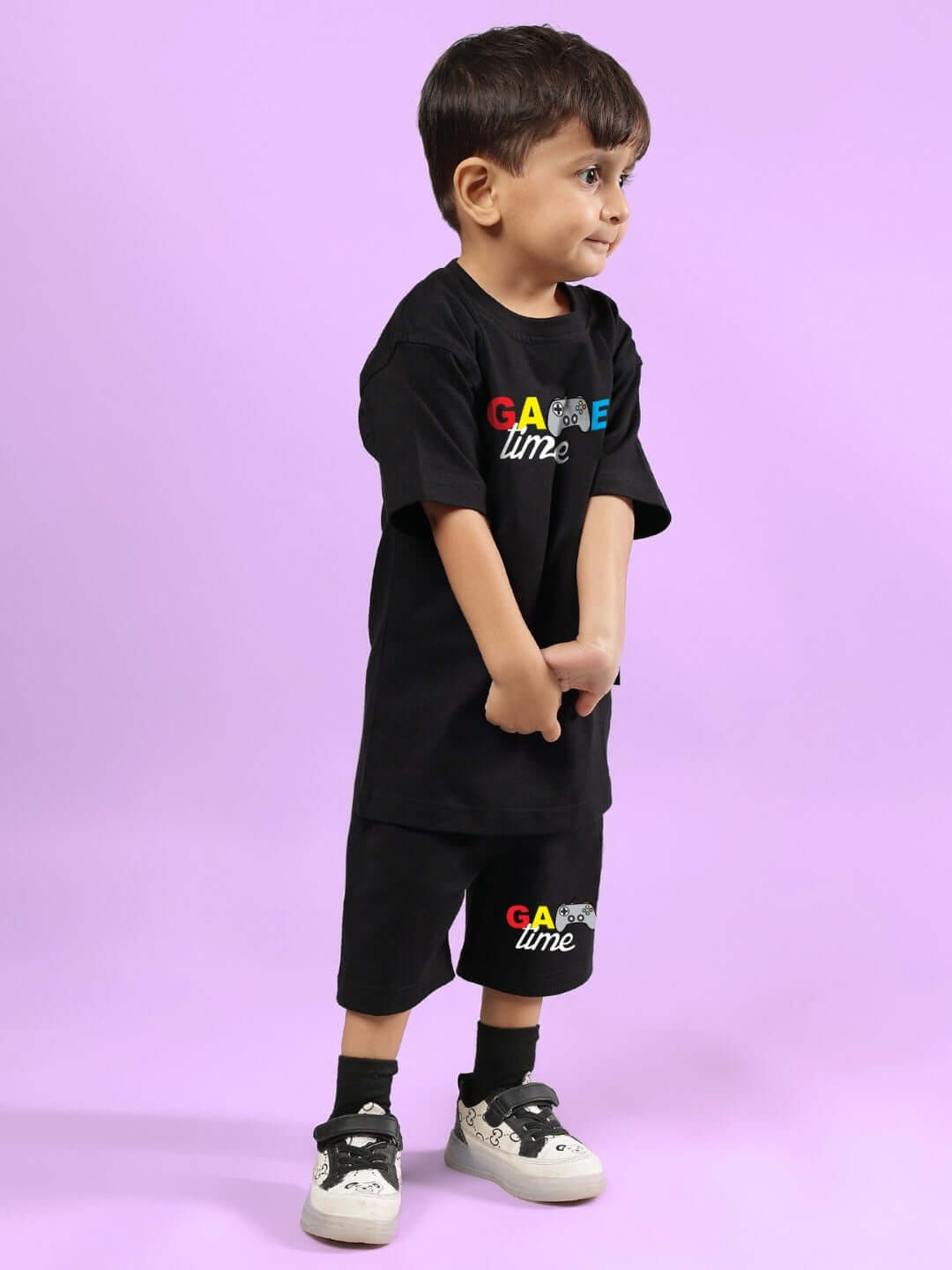 Young boy in black GAME FINISHER CO-ORD FOR BOYS & GIRLS BLACK outfit, standing against a purple background.