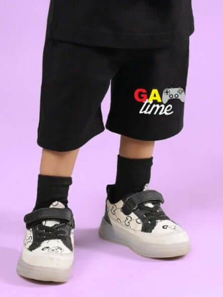 Child wearing GAME FINISHER SHORTS FOR BOYS & GIRLS BLACK with game-themed design on purple background