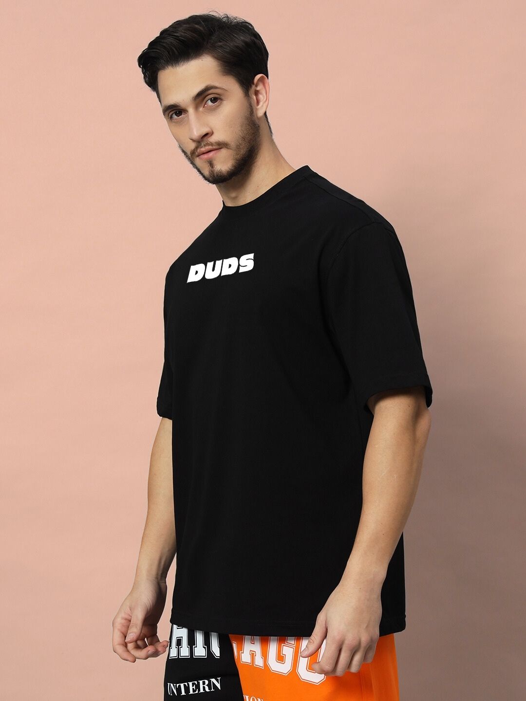 Model wearing GAME-OVER OVER-SIZED T-SHIRT BLACK with 'Duds' logo, casual fashion.