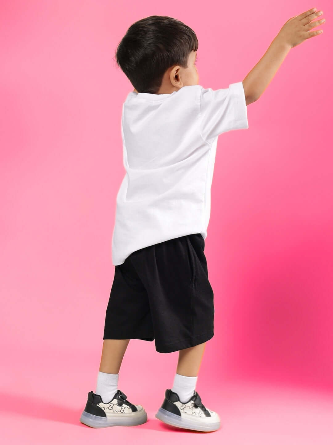 GAME TIME CO-ORD FOR BOYS & GIRLS WHITE BLACK, young child modeling stylish white tee and black shorts, pink background