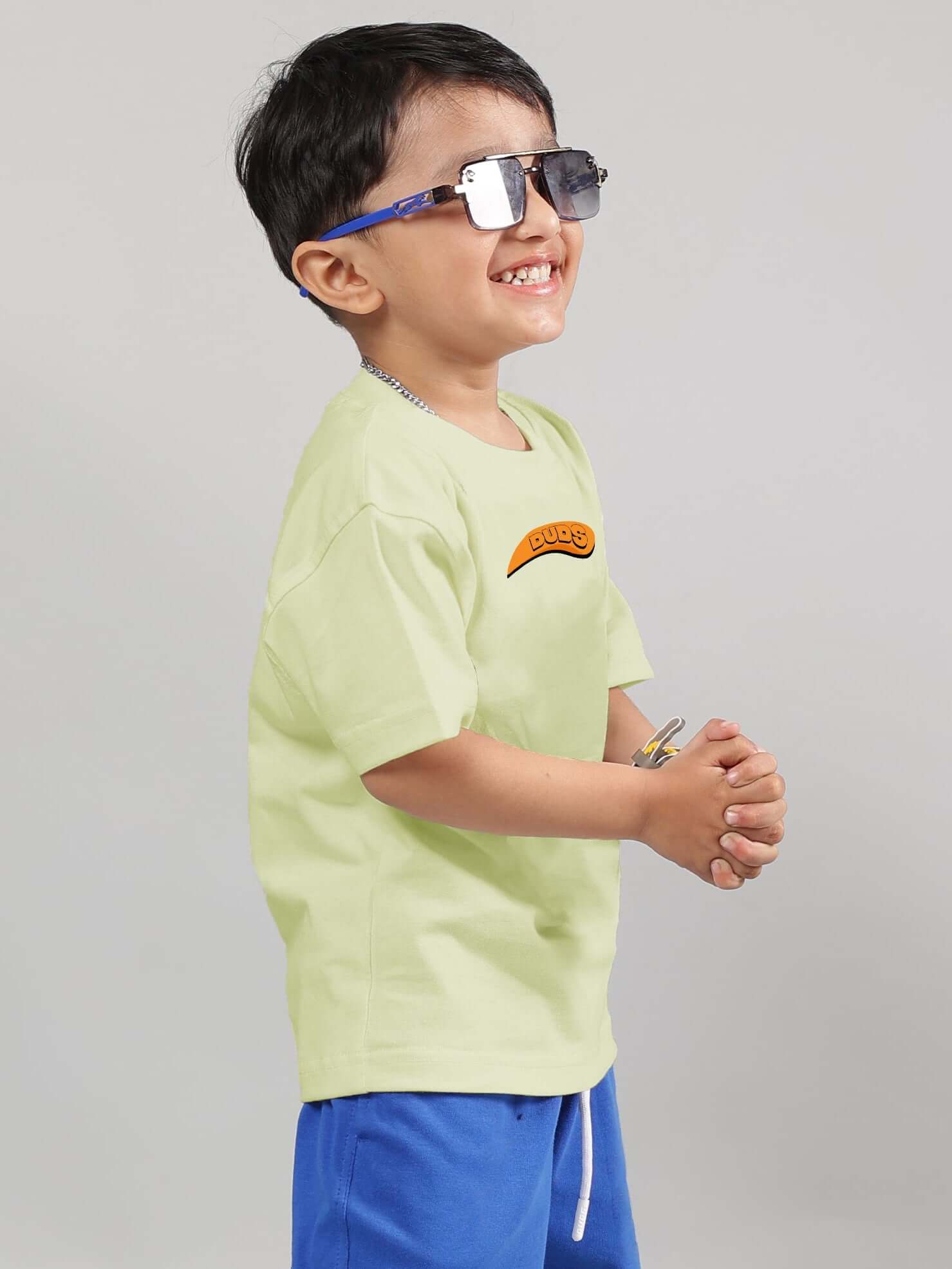 Child wearing GARFIELD T-SHIRT FOR BOYS GIRLS CELERY-ICE with blue shorts, smiling and posing in sunglasses.