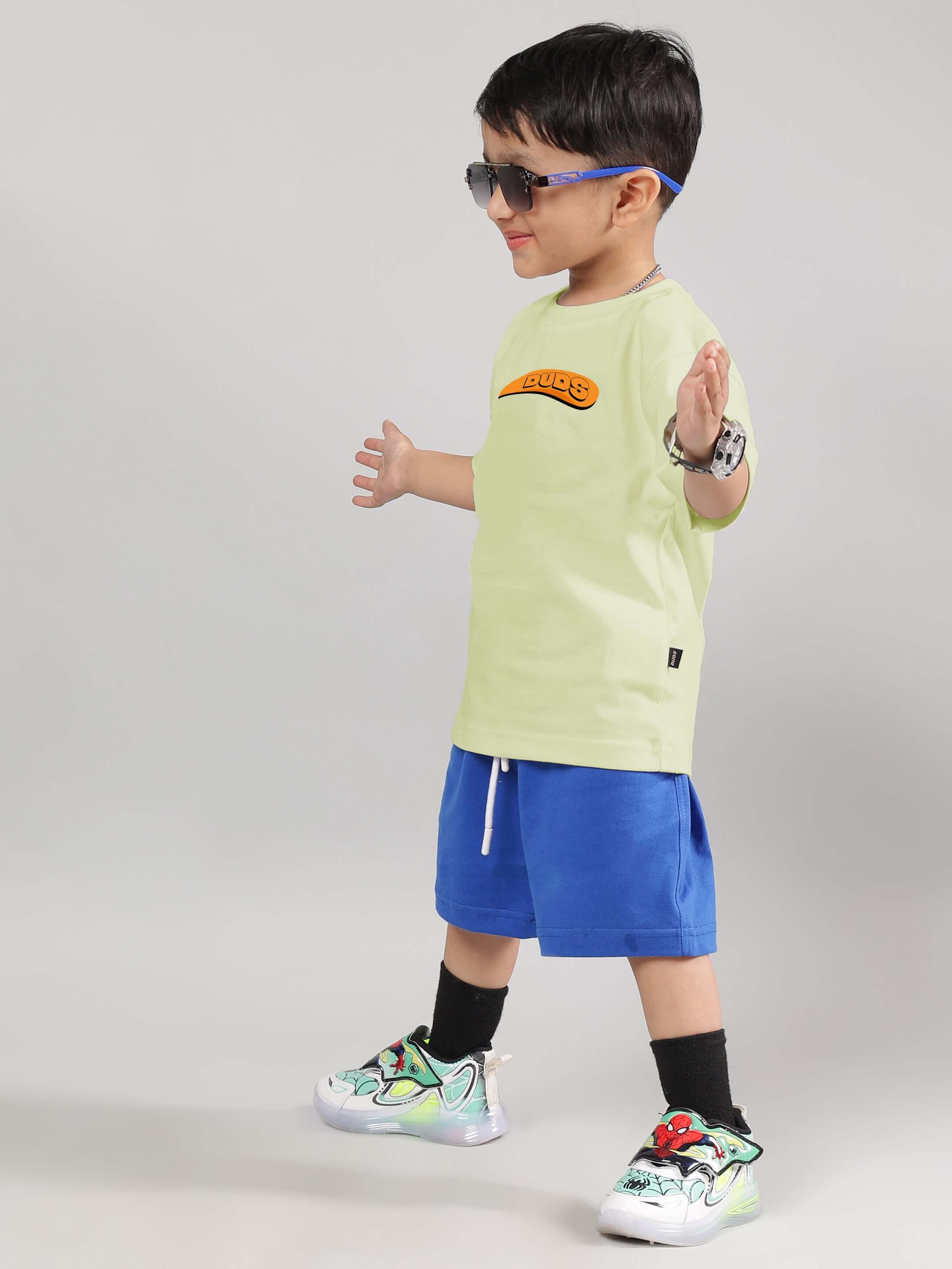 Child wearing Garfield Co-ord set in celery and ice blue with sunglasses, showcasing stylish design by DUDS Tailors.