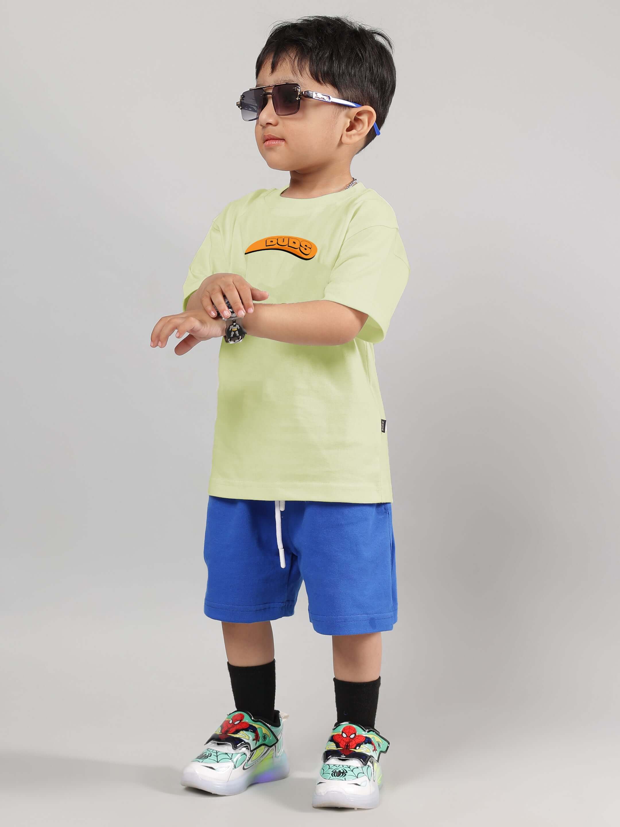 Young child wearing Garfield co-ord set in celery and ice blue, featuring a stylish DUDS t-shirt and shorts, complete with sunglasses.