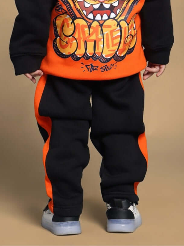 Child wearing black and orange COOL TEDDY fleece pants for boys and girls, featuring vibrant design and comfortable fit.