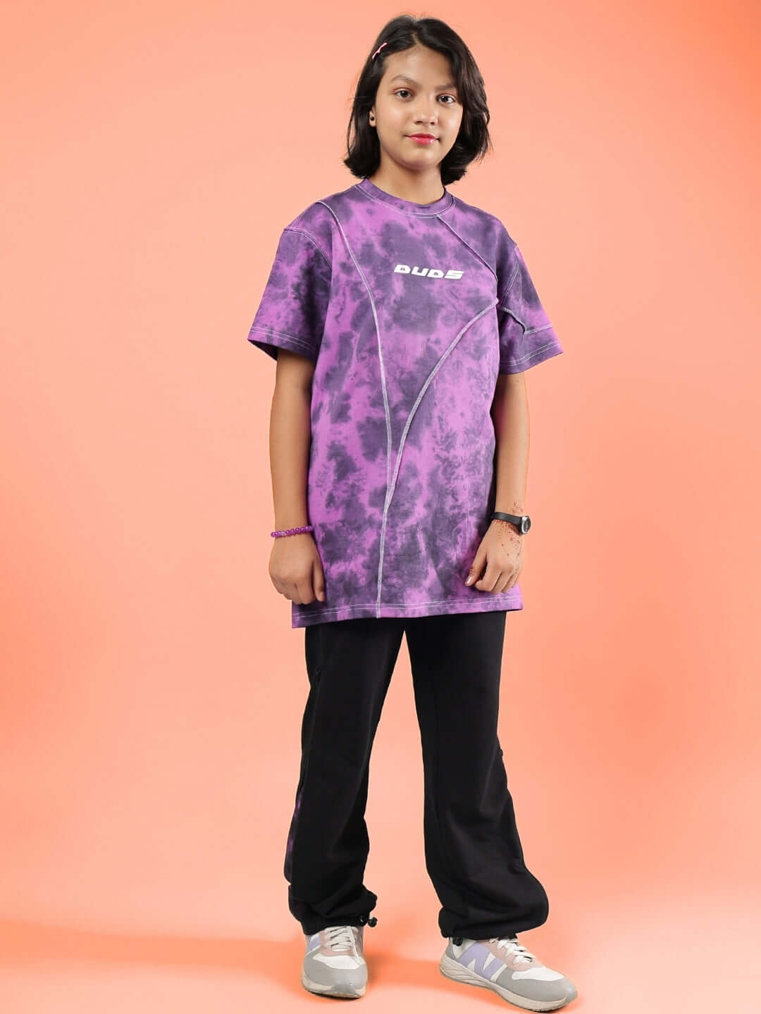 Child wearing GHOST RIDER CO-ORD FOR BOYS & GIRLS PURPLE BLACK from DUDS, smiling and posing against an orange background.