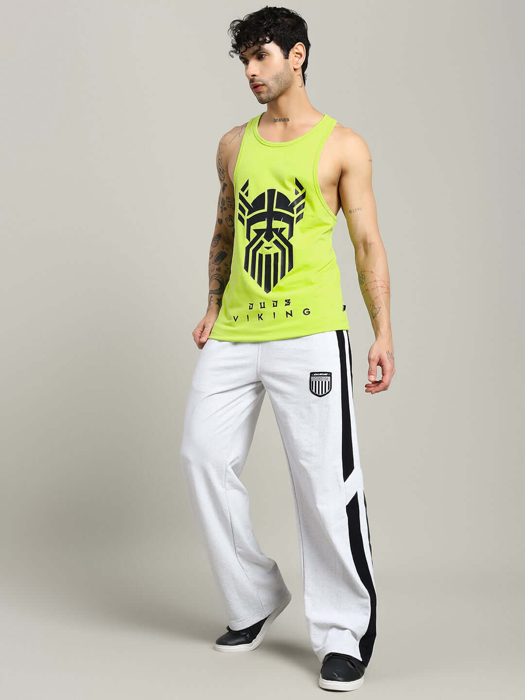 Man wearing neon green GLADIATOR GYM T-SHIRT and white pants, showcasing custom fit gym wear fashion.