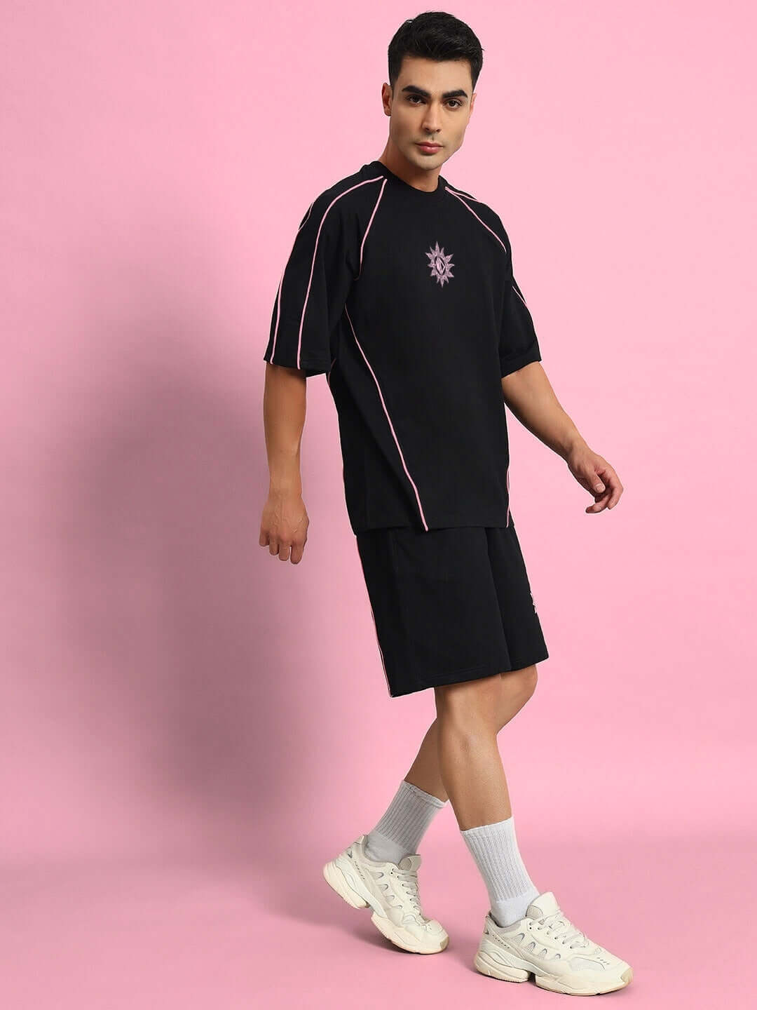 Man wearing GLARE COTTON TERRY CO-ORD SET BLACK on pink background, showcasing sporty casual fashion