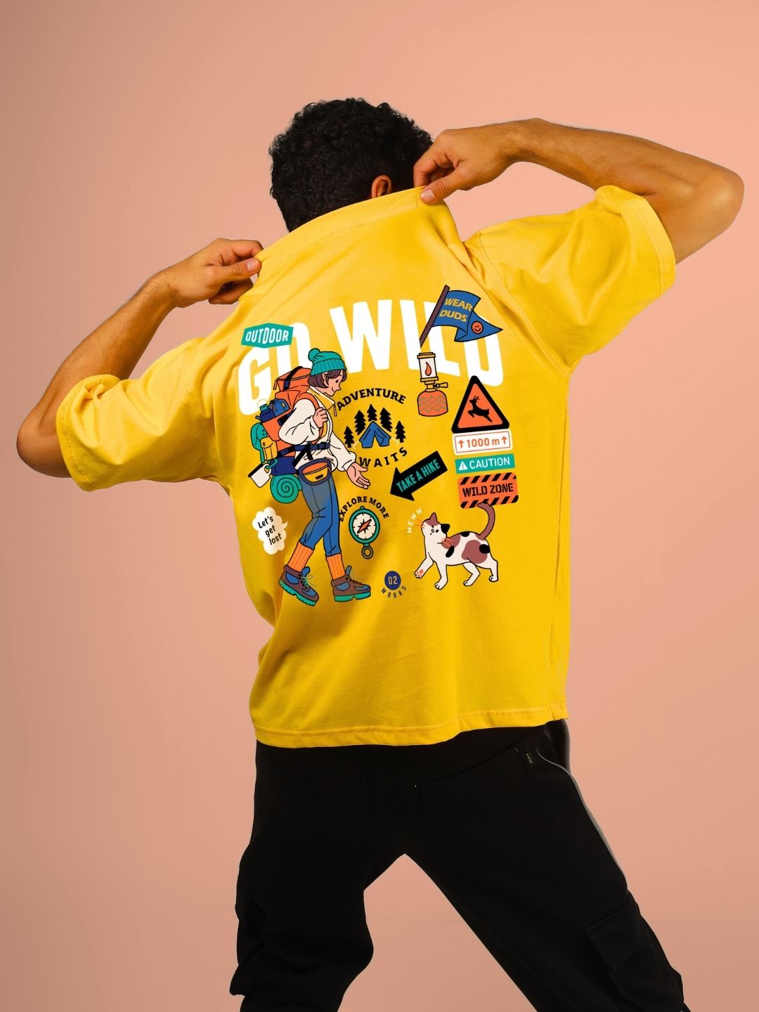 Back view of model wearing GO WILD ADVENTURE OVER-SIZED T-SHIRT YELLOW featuring graphic prints highlighting adventurous themes.