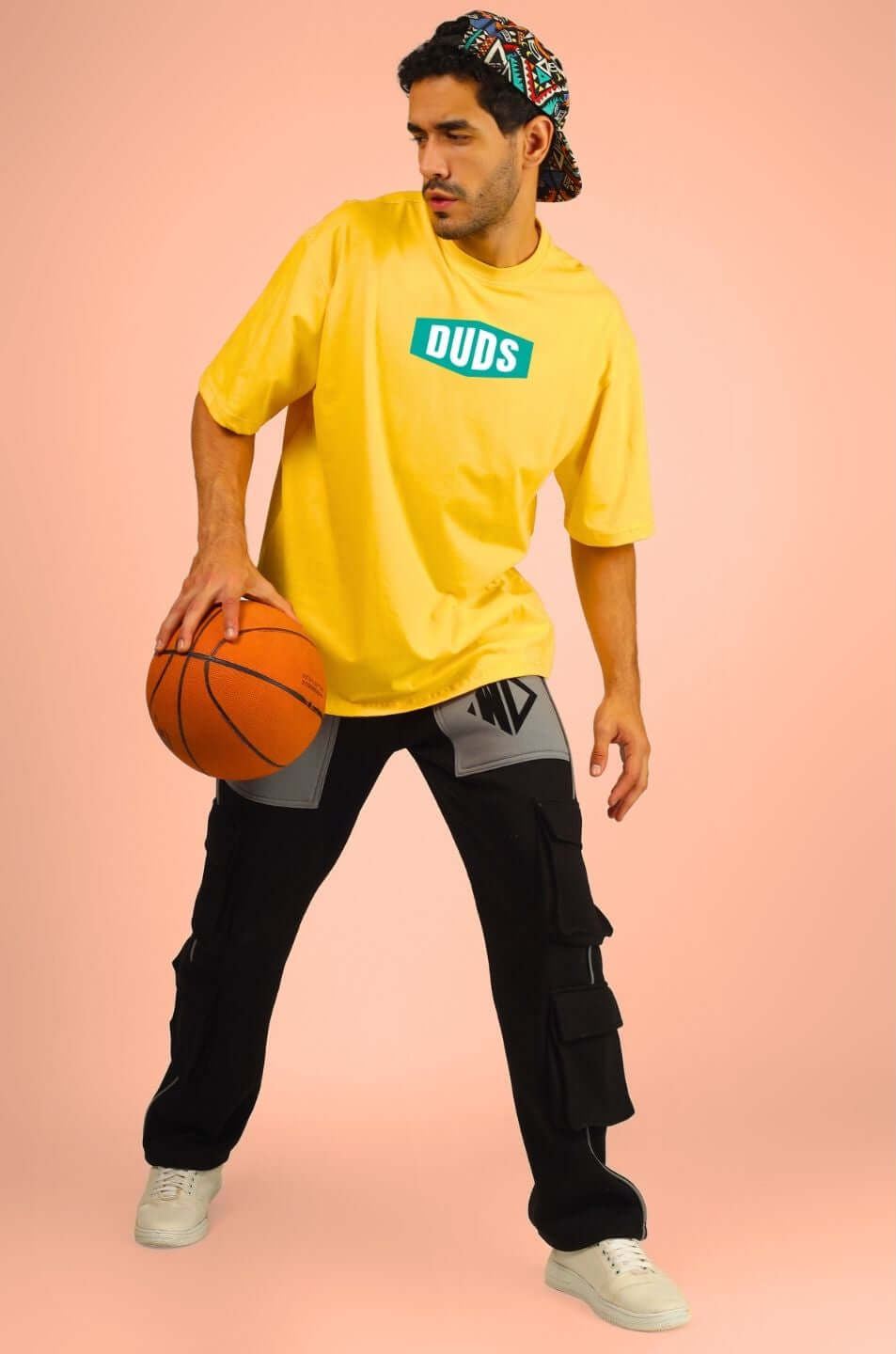 Man wearing GO WILD ADVENTURE OVER-SIZED T-SHIRT YELLOW with basketball, showcasing bold style and adventurous spirit.