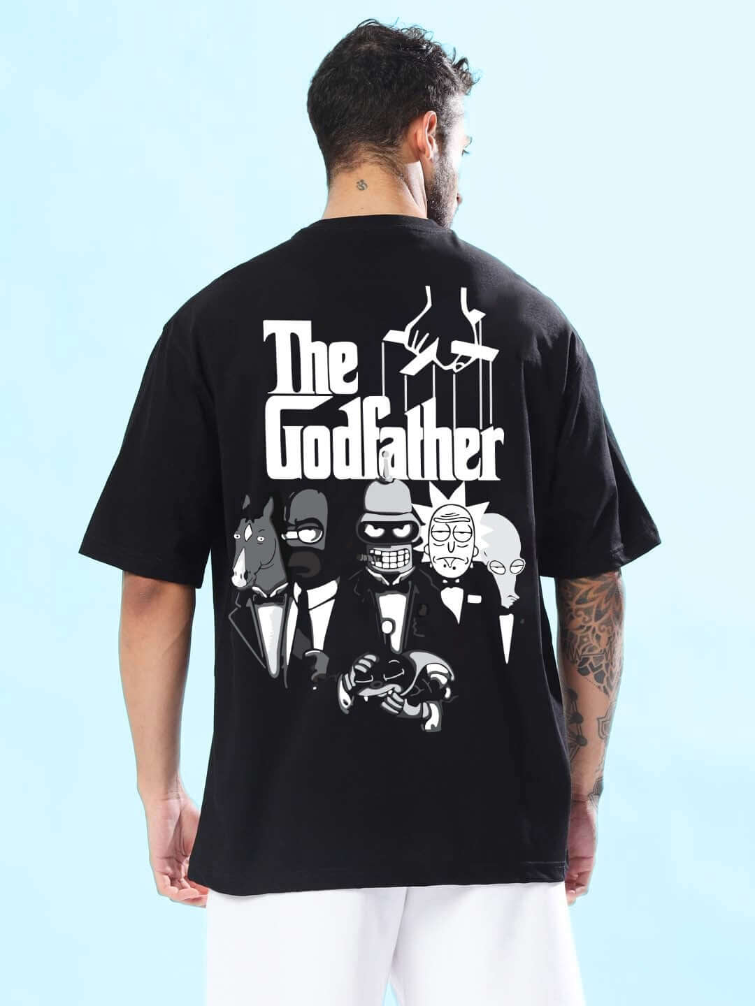 Black oversized 'Godfather' t-shirt featuring a graphic design on the back, worn by a model showing sleeve tattoo.