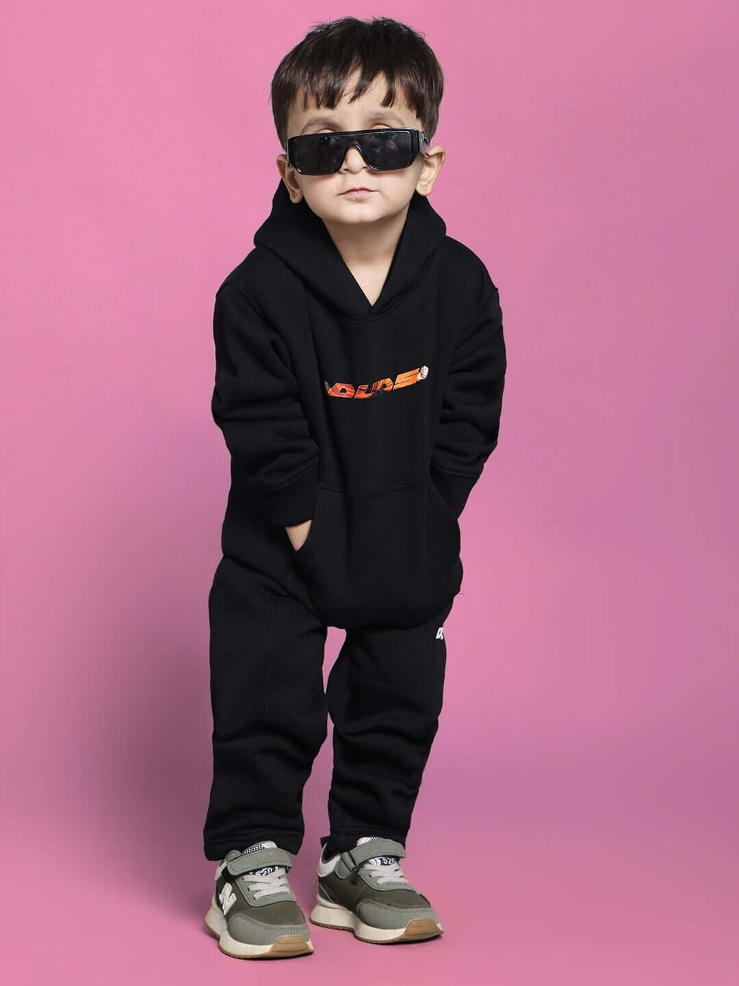 Young child wearing a black GOHAN CO-ORD FOR BOYS GIRLS BLACK set, consisting of a hoodie and pants, standing confidently against a pink backdrop.