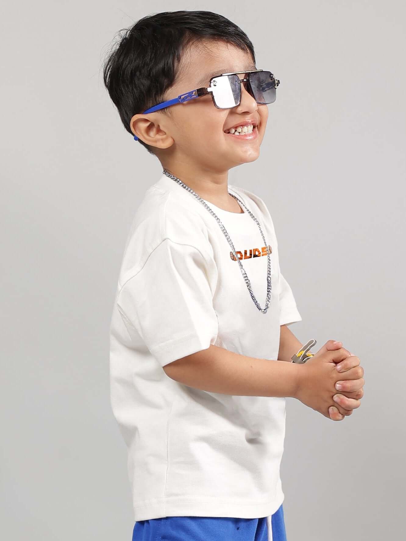 Child wearing off-white Gohan t-shirt, smiling with sunglasses and necklace, showcasing casual style. Available for custom fit orders.