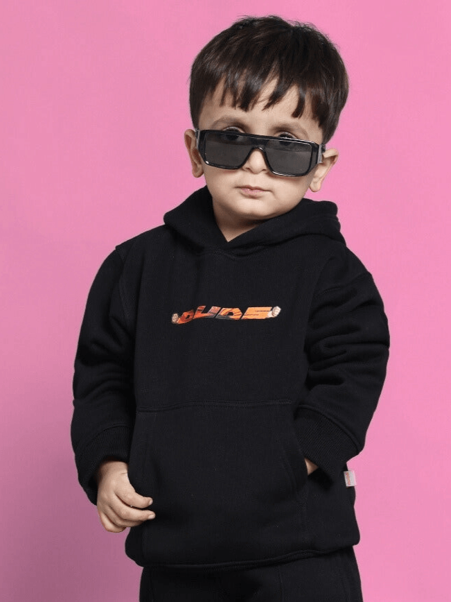 Child wearing GOHAN FLEECE HOODIE FOR BOYS GIRLS BLACK with sunglasses against pink background