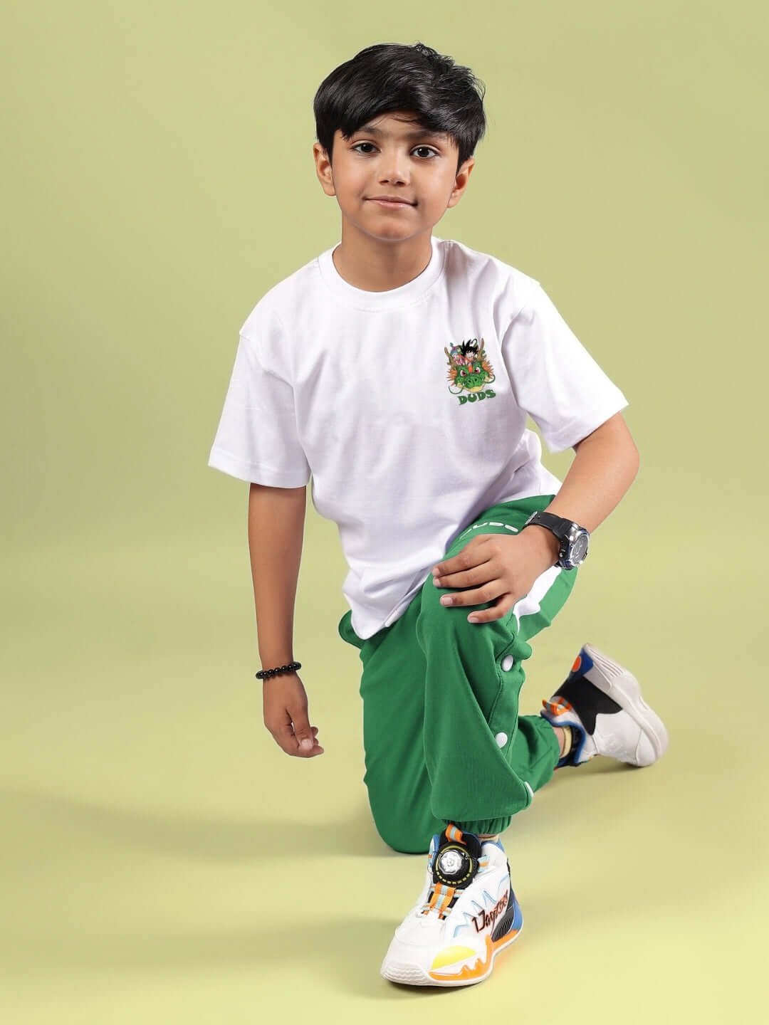 Boy wearing GOKU AND BULMA PRINTED T-SHIRT FOR BOYS GIRLS WHITE with green pants, showcasing Dragon Ball Z characters.