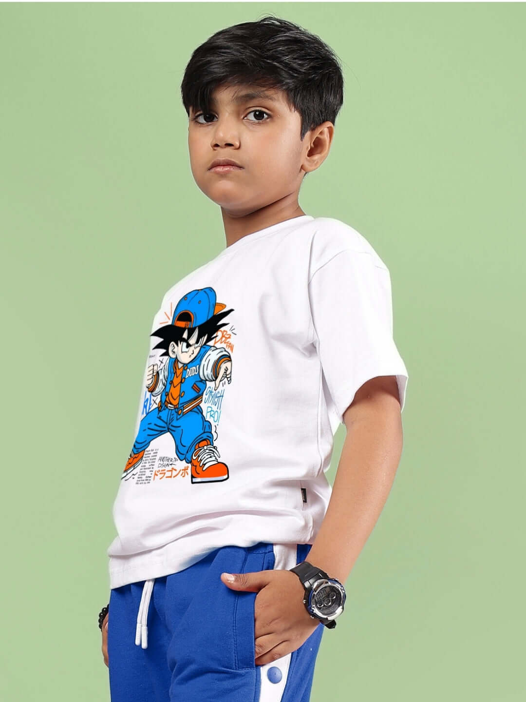 Boy wearing GOKU WARRIOR T-SHIRT FOR BOYS & GIRLS WHITE with graphic design, standing against green background.