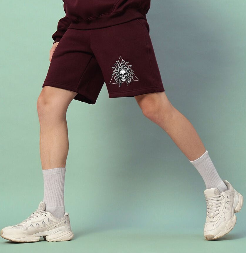 Person wearing GORGON SKULL PRINTED FLEECE SHORTS WINE with white socks and sneakers
