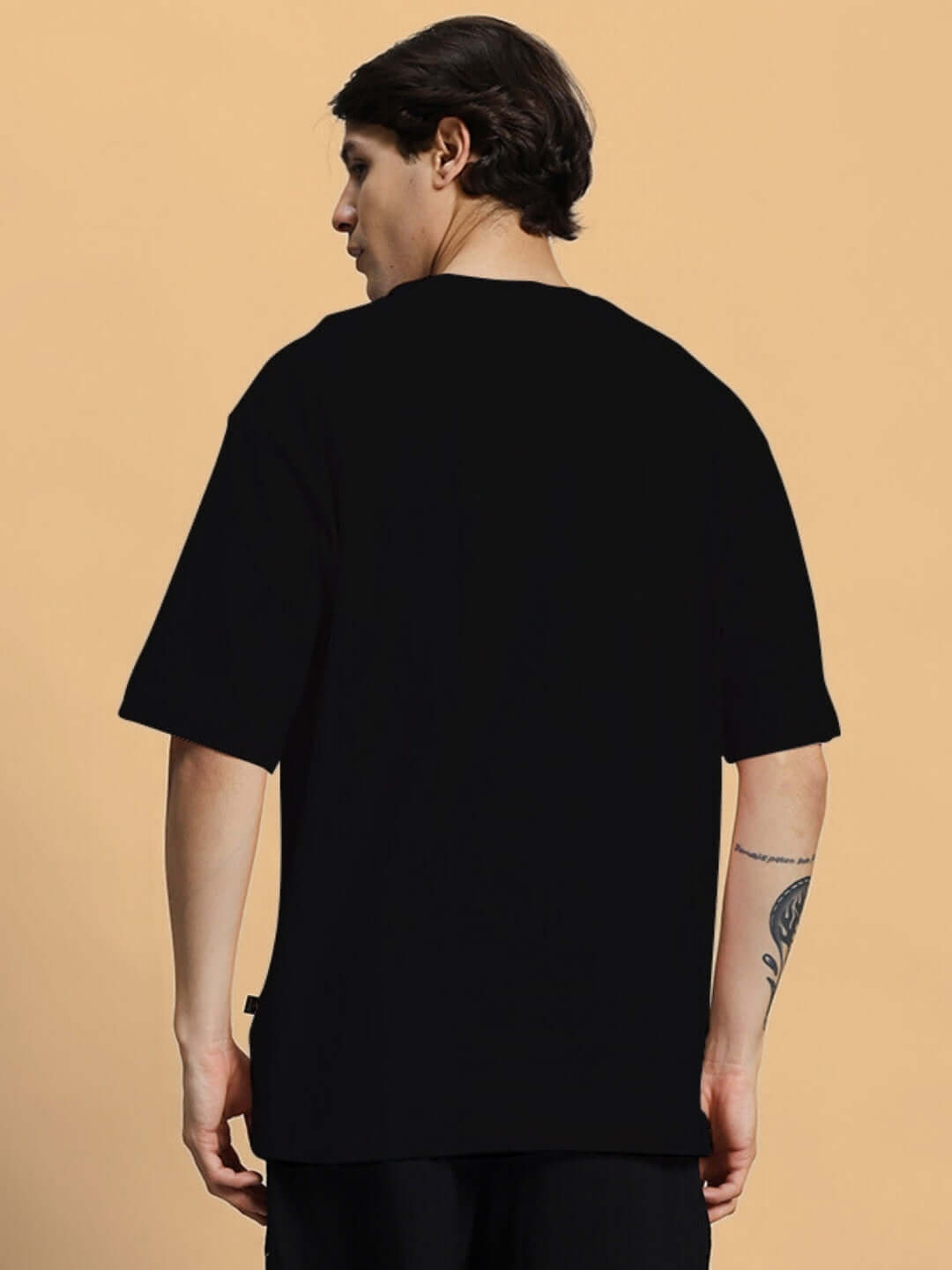 Back view of model wearing GREAT PRINTED OVERSIZED T-SHIRT BLACK made of 100% cotton with premium heavy gauge fabric.