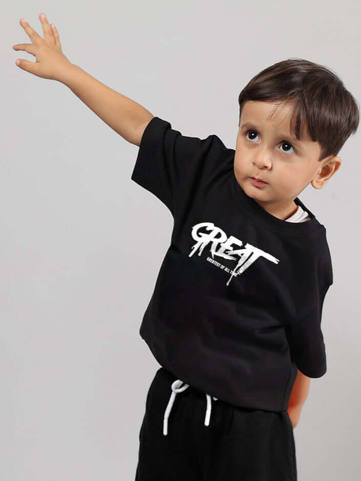 Black oversized t-shirt for boys & girls with 'GREAT' print, worn by a child, available in custom fit options at DUDS.