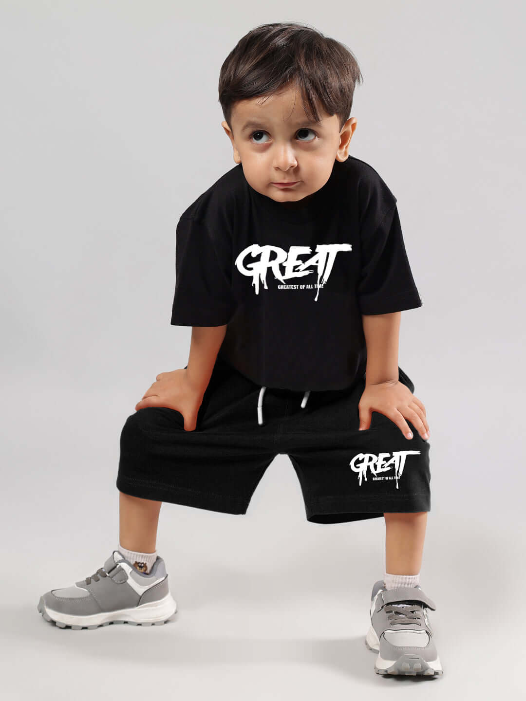 Young child wearing a black oversized t-shirt with 'GREAT' print, designed for boys and girls by DUDS, perfect for casual wear.