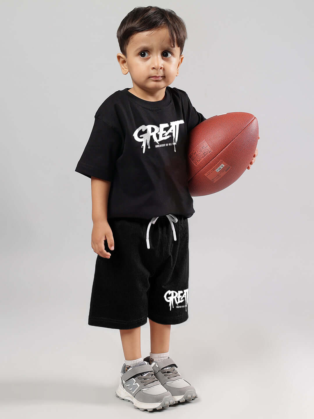 Child wearing GREAT PRINTED SUMMER CO-ORD FOR BOYS GIRLS BLACK holding a football.