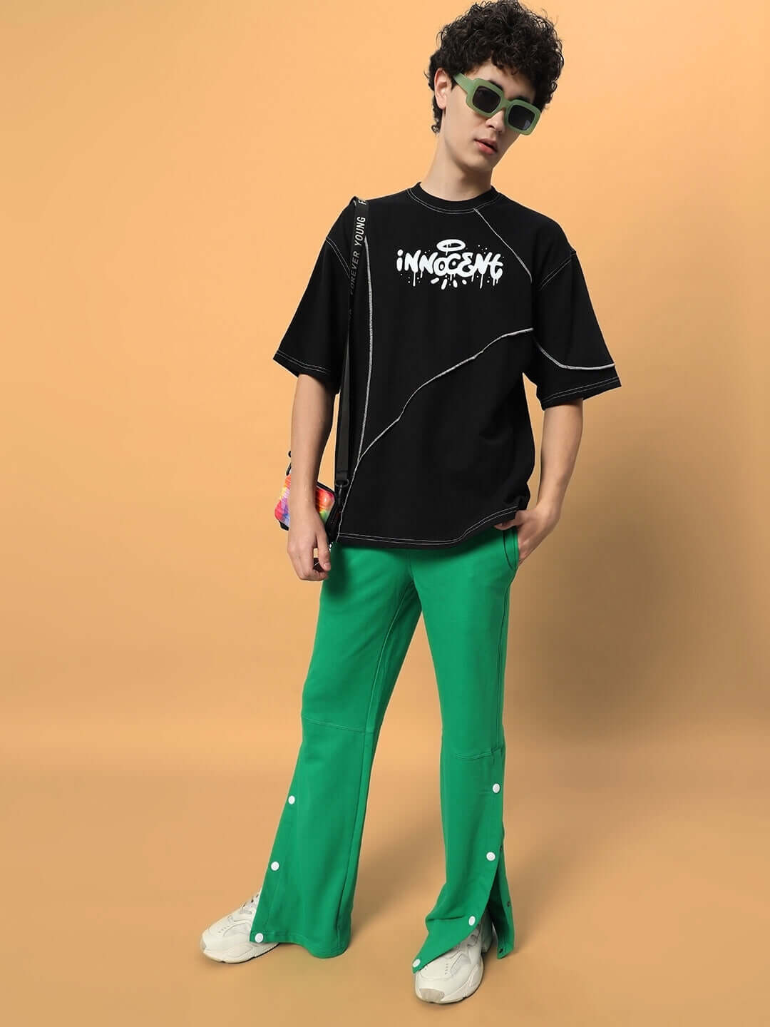 Model wearing DUDS RACER JOGGERS in green with custom fit option, showcasing casual streetwear style with black graphic tee.