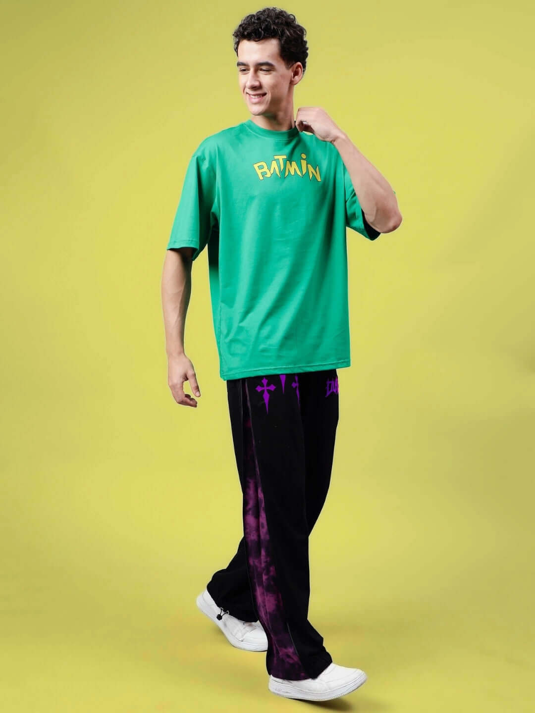 Model wearing green t-shirt and black joggers with purple zipper panel, showcasing casual stylish outfit