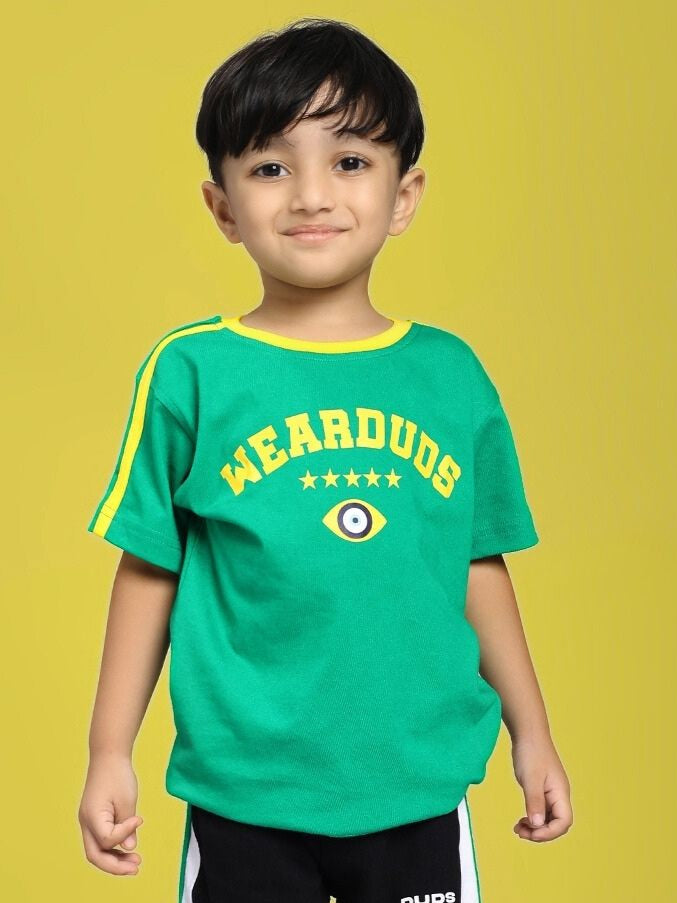 Child wearing IRISH T-SHIRT FOR BOYS AND GIRLS GREEN with "WEARDUDS" text and eye emblem on a yellow background.