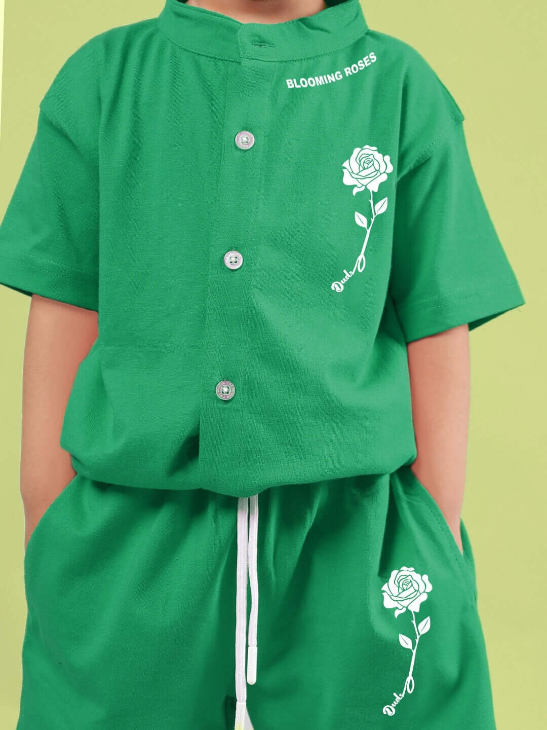 Child wearing LIMBO CO-ORD FOR BOYS & GIRLS GREEN, featuring a green shirt and shorts with white rose designs, ideal for comfort and style.