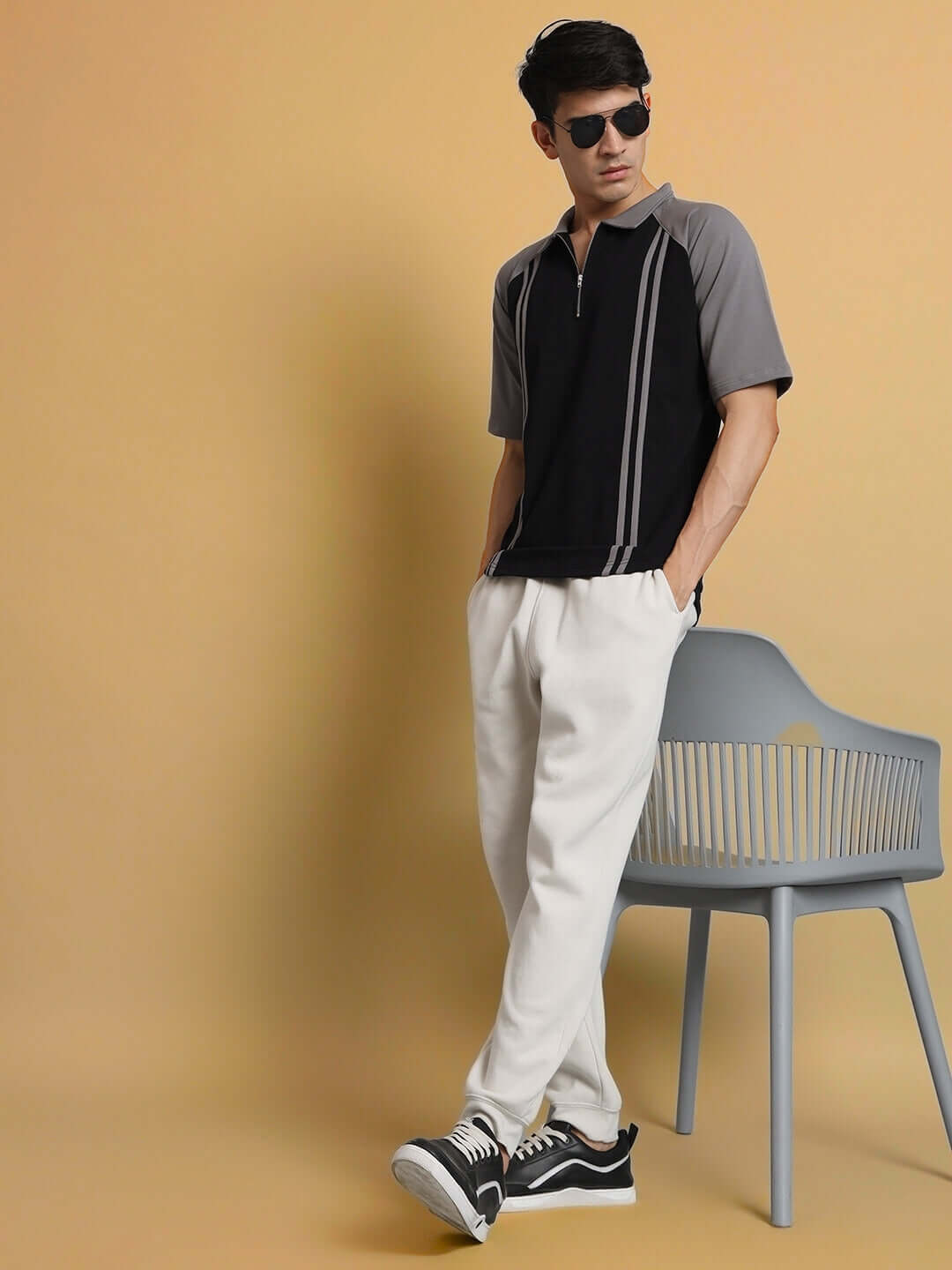 Model wearing grey stripe black raglan t-shirt with white pants, showcasing casual fashion style