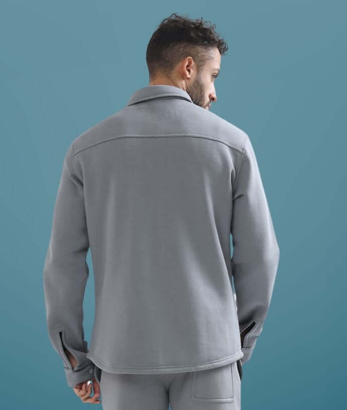 Rear view of a man wearing a grey relaxed fit overshirt with long sleeves and a casual collar made by DUDS.