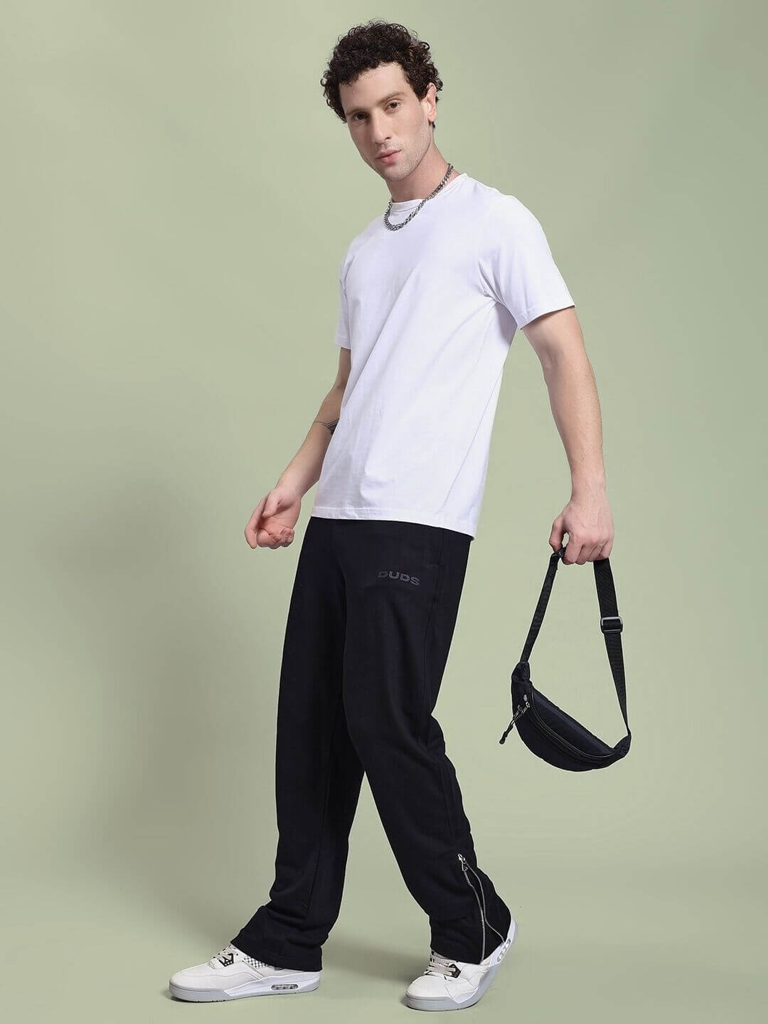 Model wearing JOSS WINS RELAXED-FIT JOGGER BLACK with white t-shirt and holding a black sling bag.