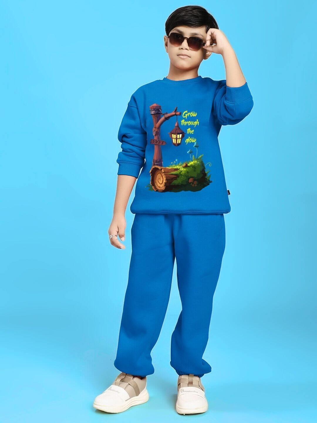 Child wearing GROW AND GLOW PRINT FLEECE CO-ORD FOR BOYS AND GIRLS BLUE outfit against blue background.