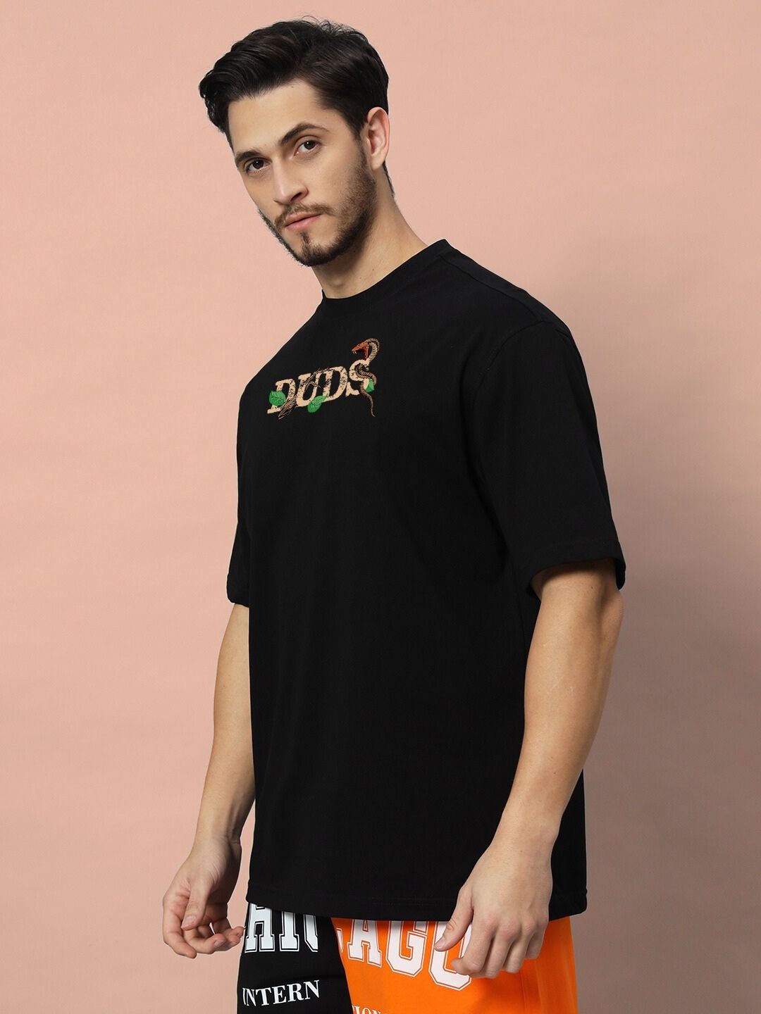 Model wearing HAND SNAKE APPLE OVERSIZED T-SHIRT BLACK with graphic design, standing against a neutral background.