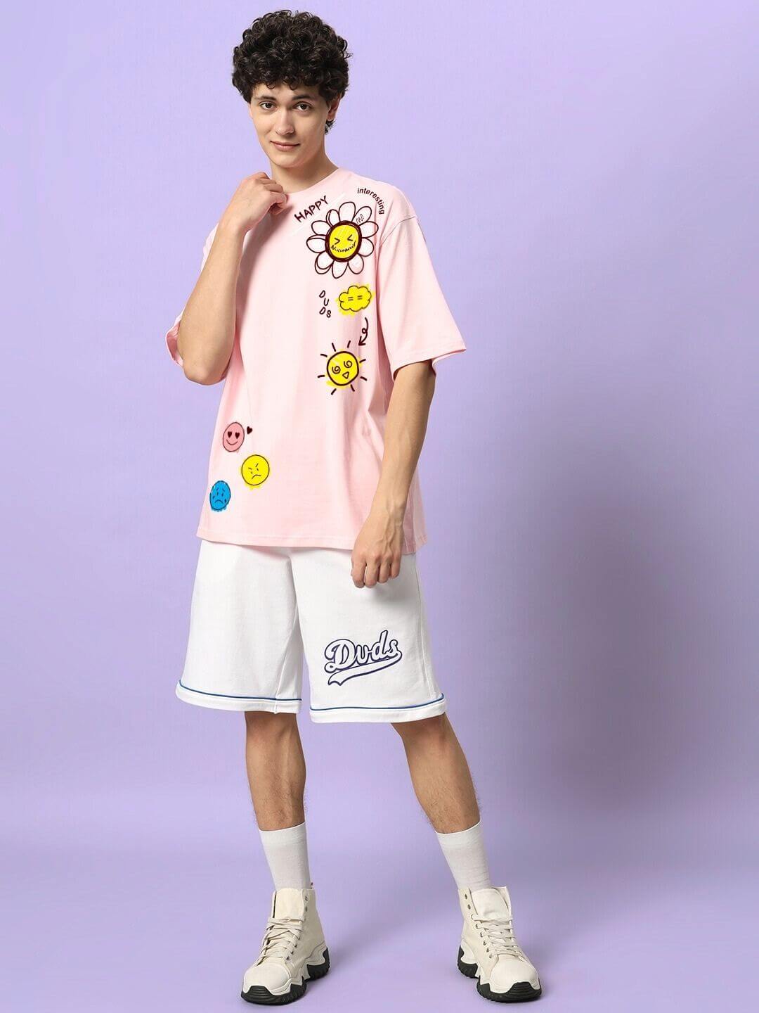 Model wearing HAPPY INTERESTING OVERSIZED T-SHIRT PINK with playful graphics, standing against a purple background, epitome of streetwear style.