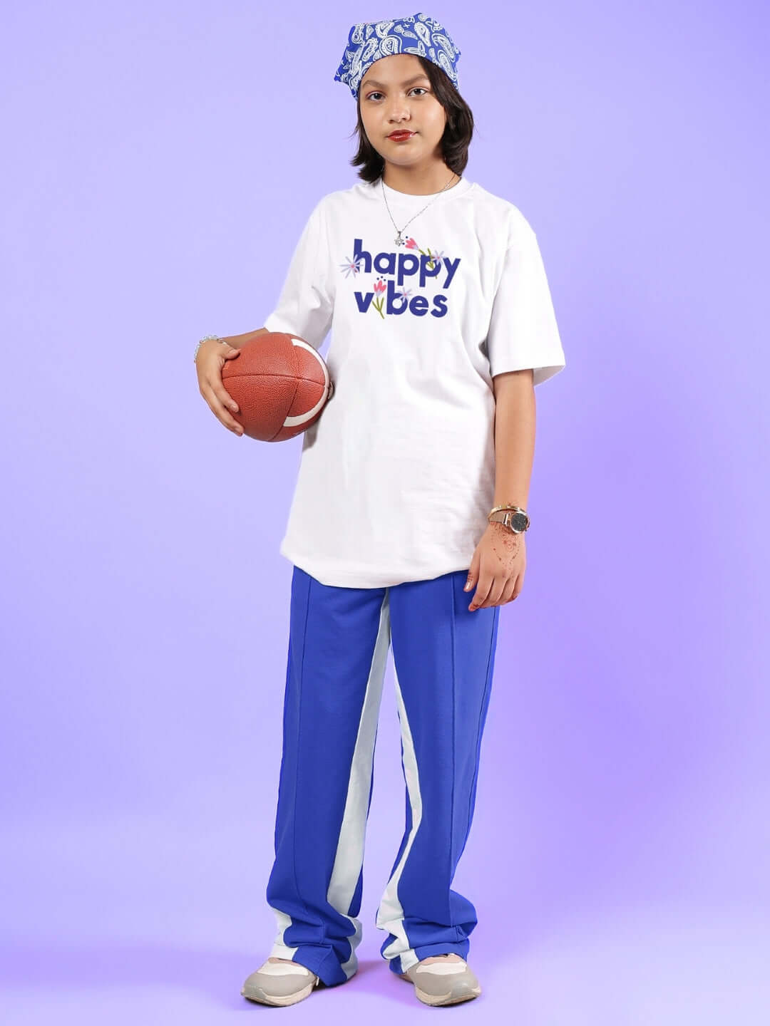 Child wearing HAPPY VIBES CO-ORD FOR BOYS & GIRLS WHITE-BLUE with a basketball against purple background