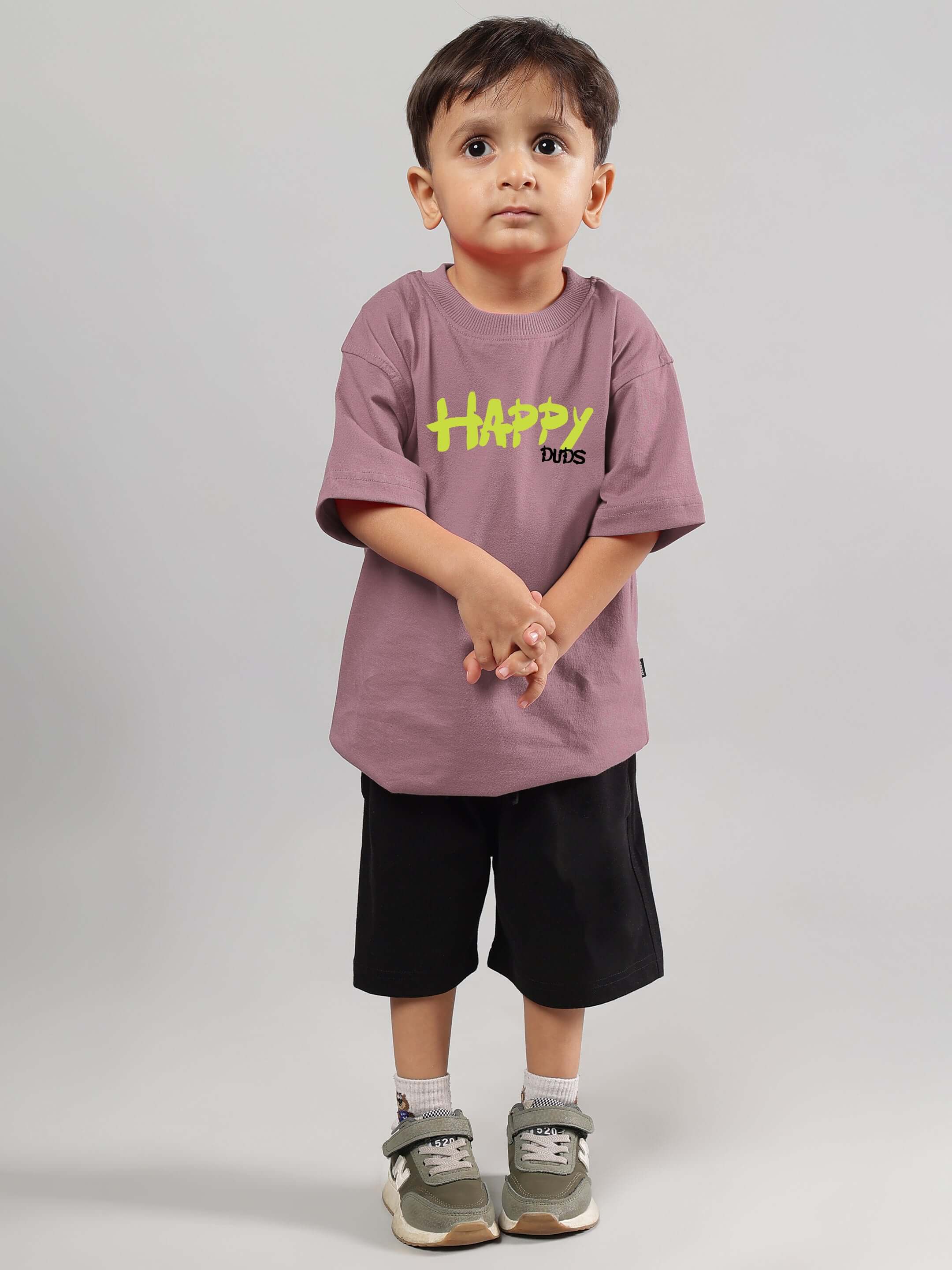 Child wearing Happy Duds oversized t-shirt in Chinese Violet, paired with black shorts and sneakers, showcasing comfortable fit.