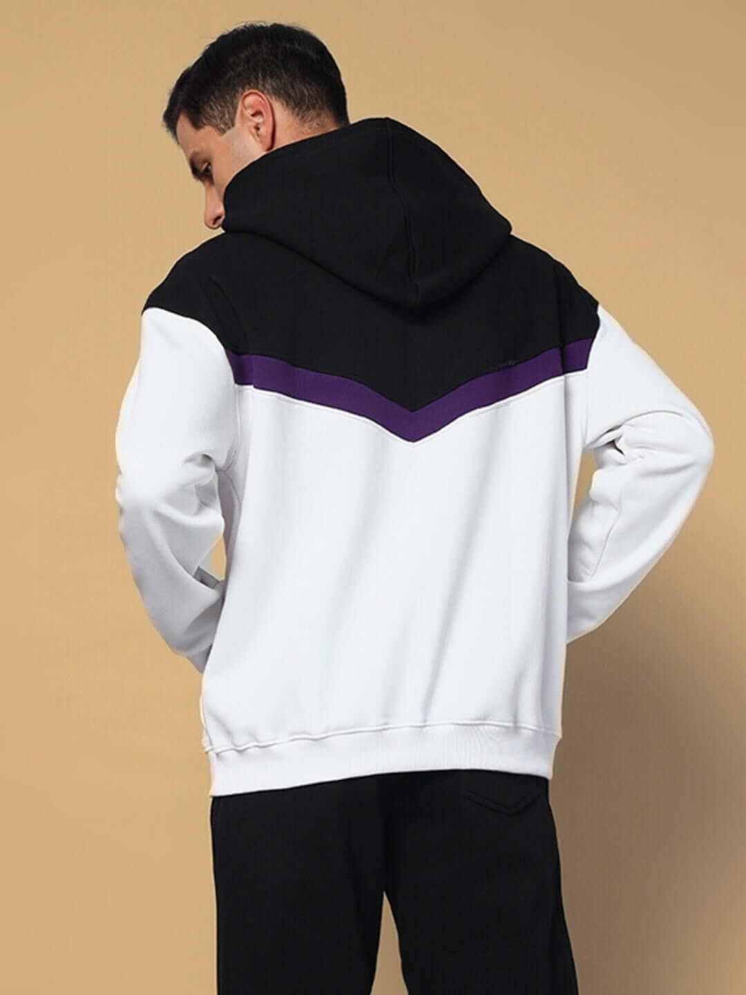 Man wearing HARLEY FLEECE COLORBLOCK HOODIE WHITE PURPLE from the back, showcasing the vibrant colorblock design on a beige background.