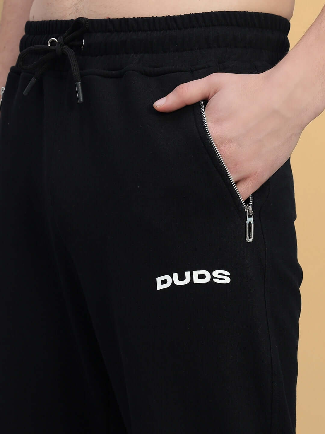 Close-up of black HARPER RELAXED FIT JOGGER by DUDS with zipper pocket and logo. Made-to-order, customizable size available.