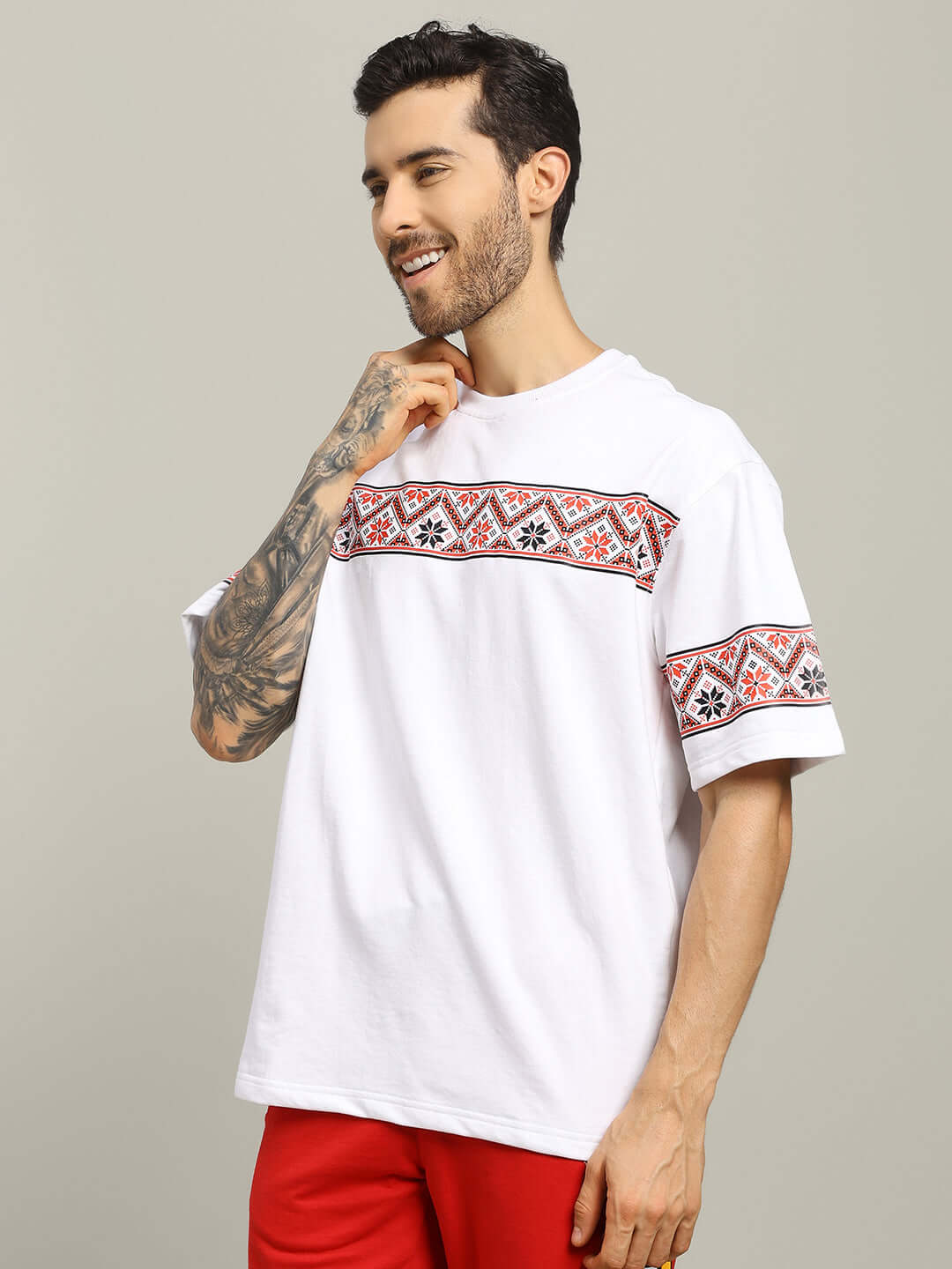Model wearing HEADPHONES ORNAMENT PRINTED T-SHIRT WHITE with vyshyvanka-inspired pattern on a white fabric.