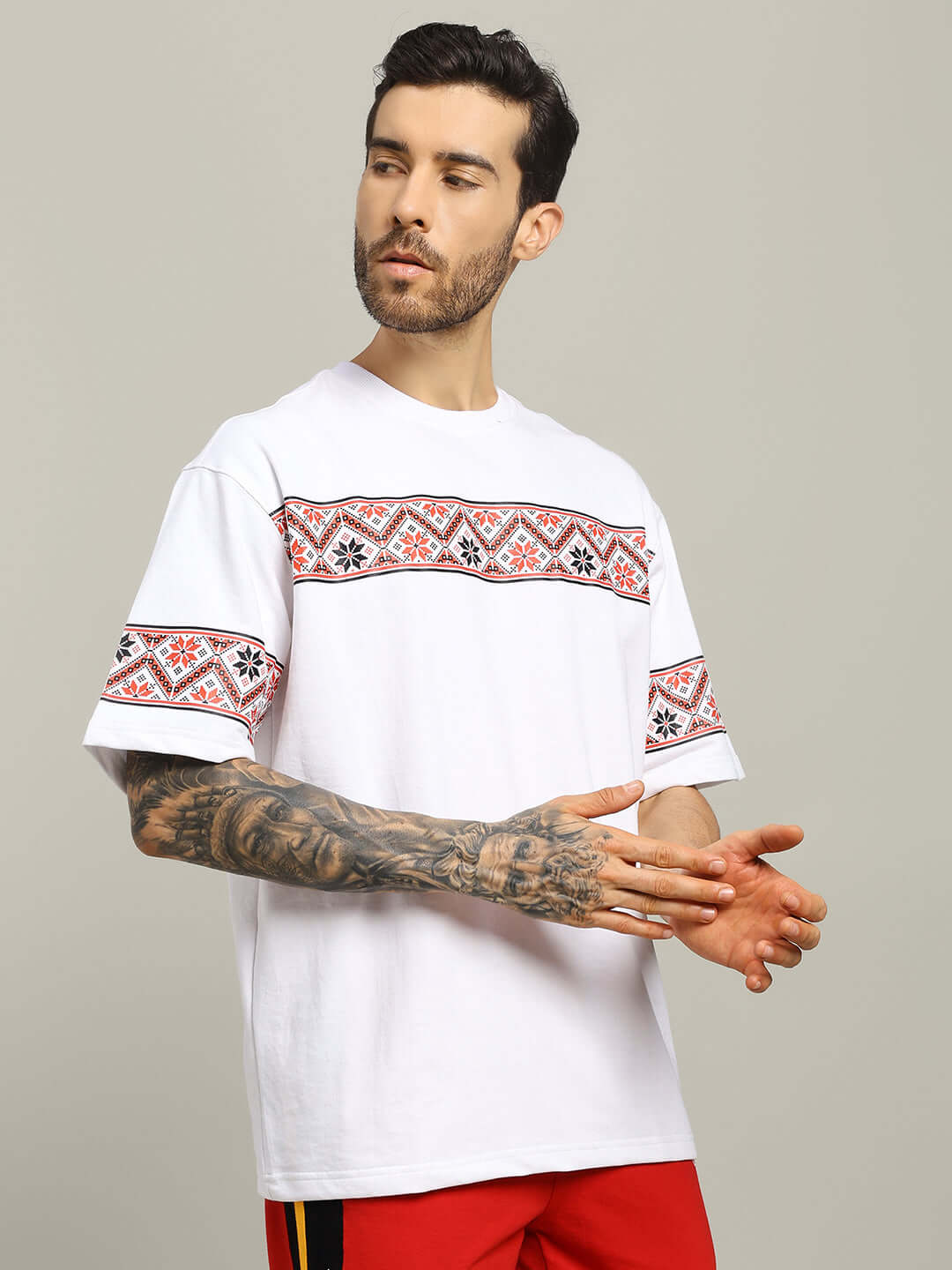 Man wearing HEADPHONES ORNAMENT PRINTED T-SHIRT WHITE, featuring a vyshyvanka-inspired design on a white tee, perfect for casual streetwear.