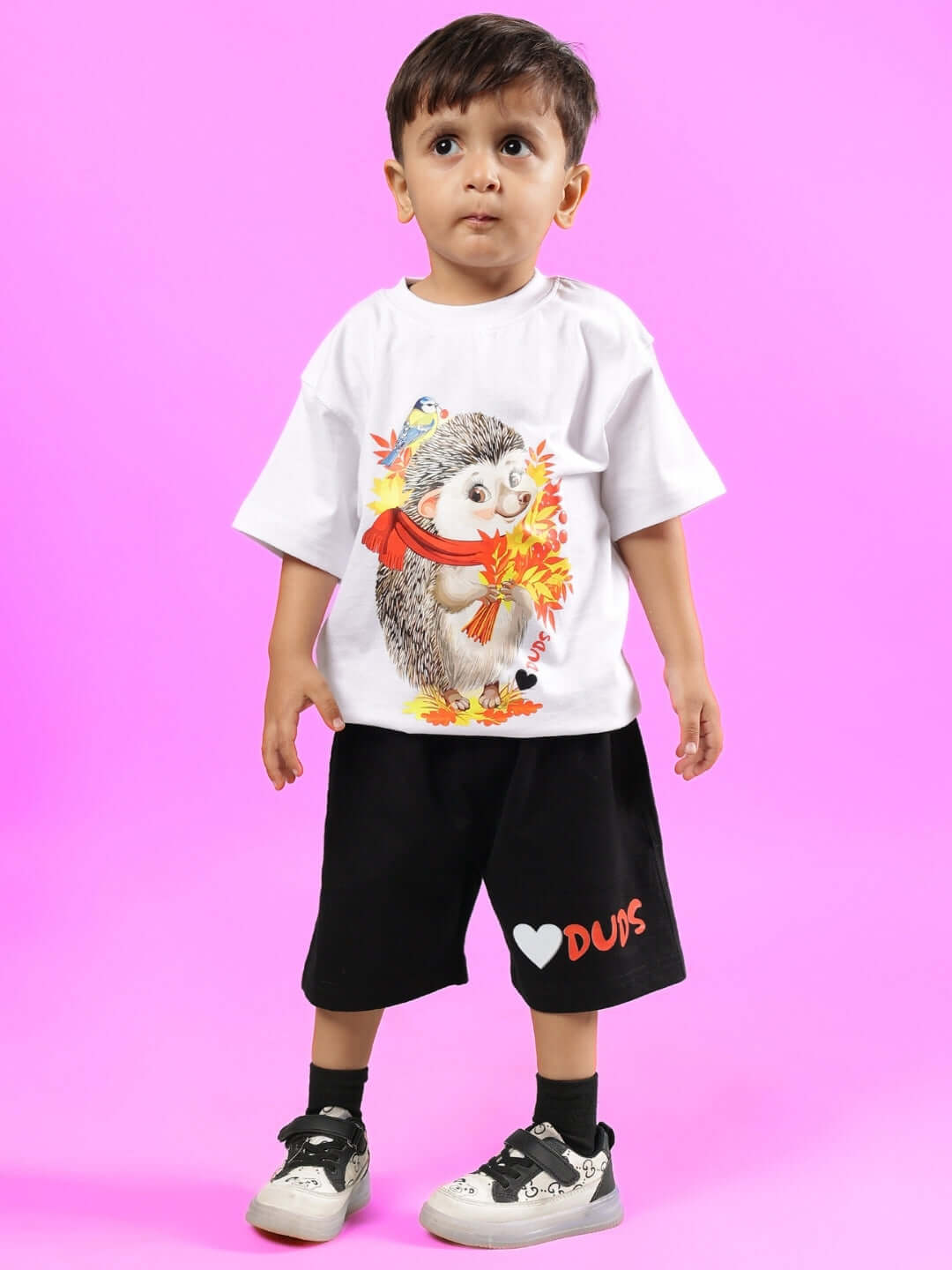 Child wearing HEDGEHOG CO-ORD FOR BOYS & GIRLS WHITE-BLACK outfit with hedgehog print, standing on pink background, kids fashion by DUDS.