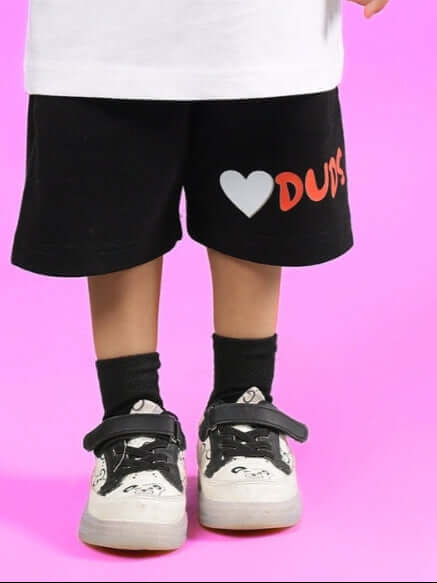 Child wearing HEDGEHOG SHORTS FOR BOYS & GIRLS BLACK with "I love DUDS" design on pink background.