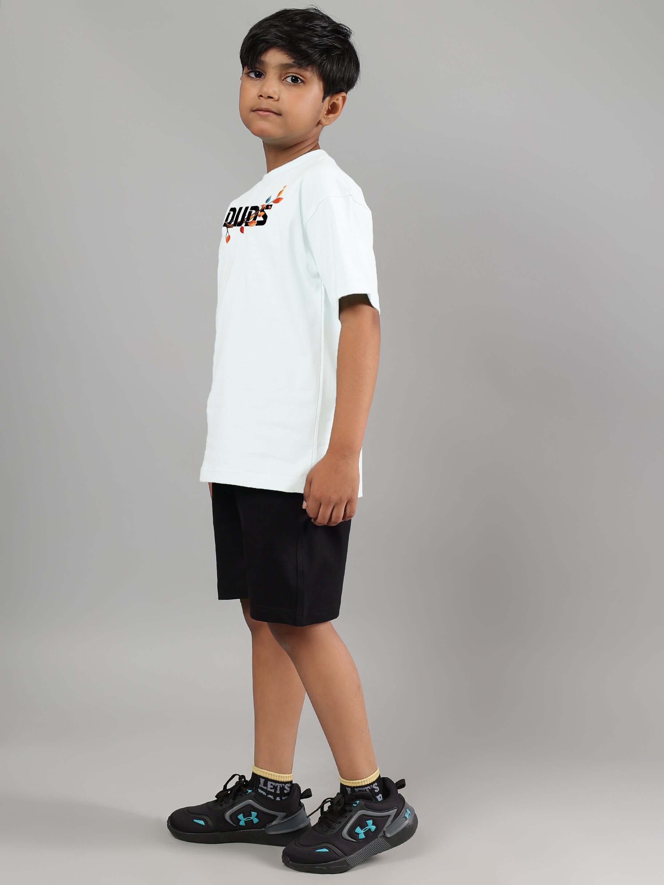 Boy wearing HEDWIG CO-ORD in white and black, featuring a DUDS logo, standing against a grey background.