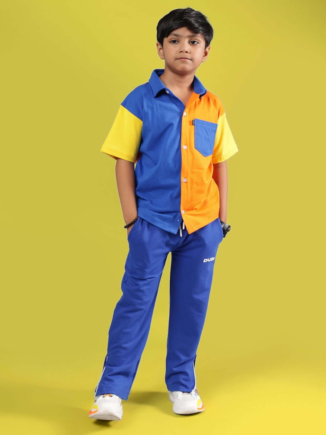Child wearing HERSHEY JOGGER FOR BOYS & GIRLS ROYAL BLUE, standing confidently against a yellow background.