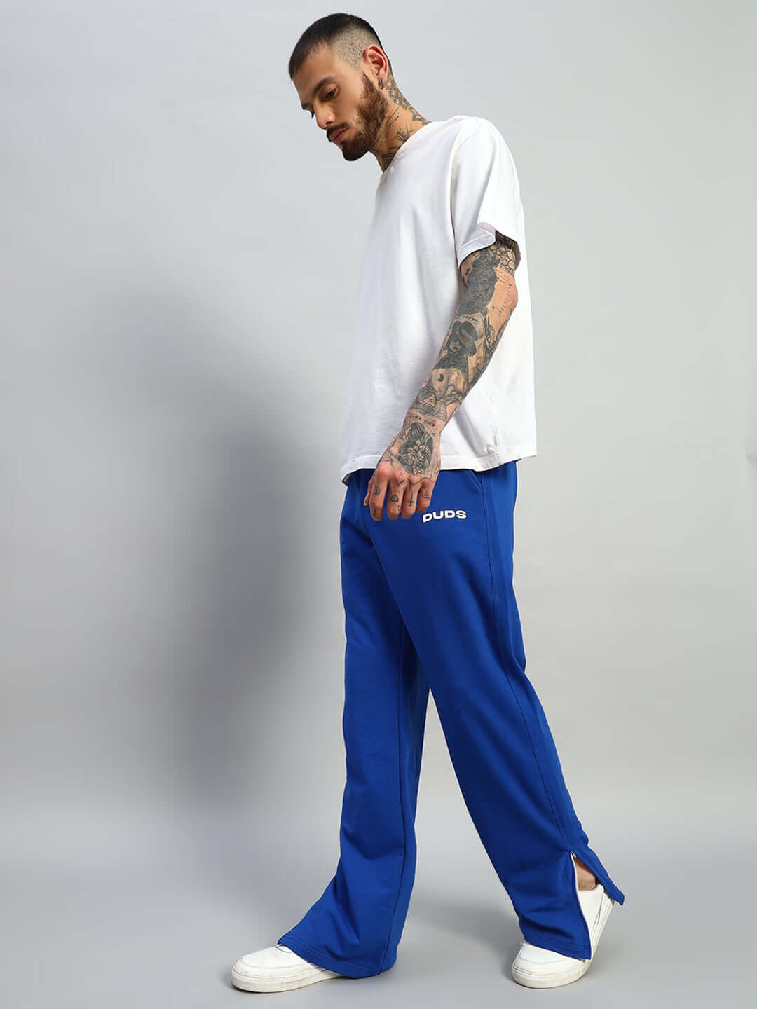Man wearing Hershey side slit joggers in royal blue from DUDS with white t-shirt and sneakers.
