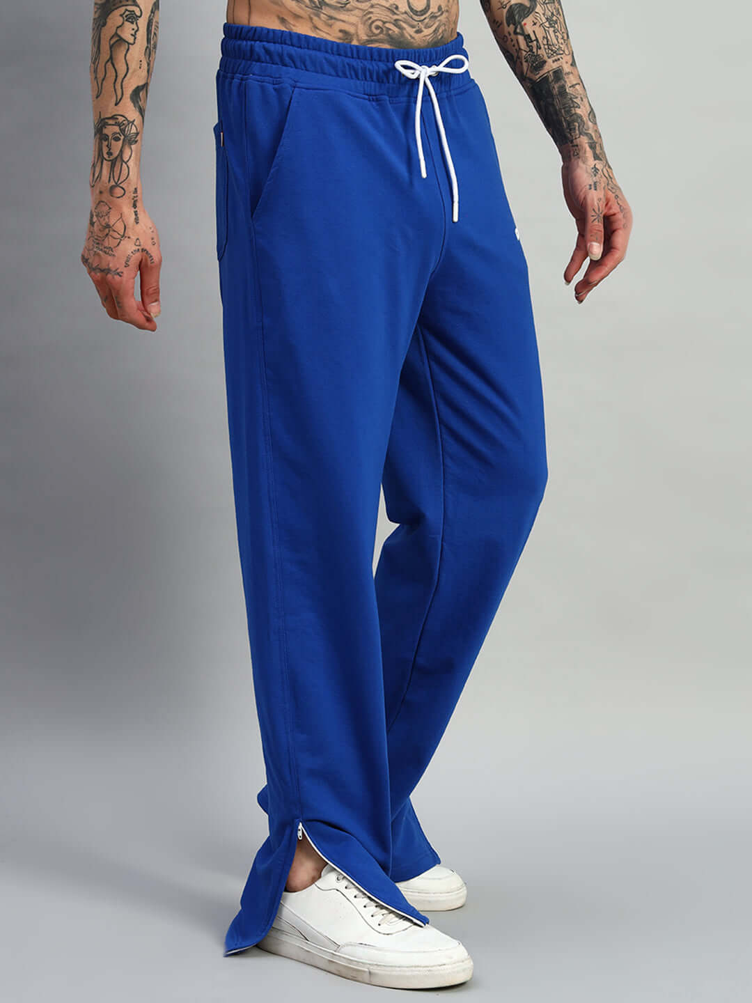 Royal blue joggers with side slits, modeled with white sneakers, showcasing comfortable fit and stylish design by DUDS.