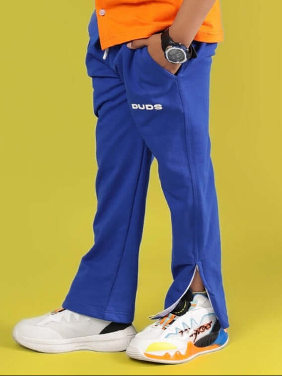 Child wearing HERSHEY JOGGER FOR BOYS & GIRLS ROYAL BLUE with colorful sneakers on yellow background.