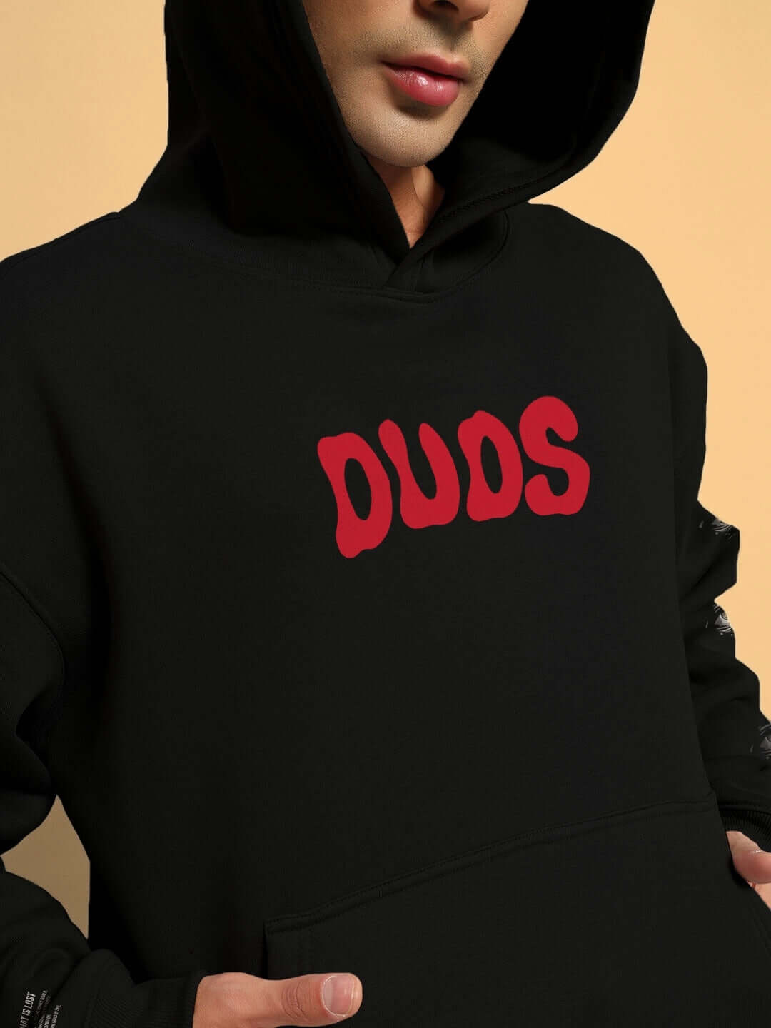 Person wearing a black oversized hoodie with red 'DUOS' text, showcasing the cozy fleece design and relaxed fit.